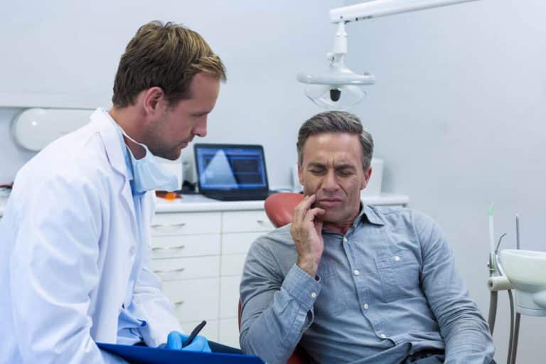 Dentist providing emergency dental care for a patient experiencing severe toothache, jaw pain, or injury, ensuring swift and effective treatment at Midland Dental Clinic to alleviate discomfort and address urgent dental issues